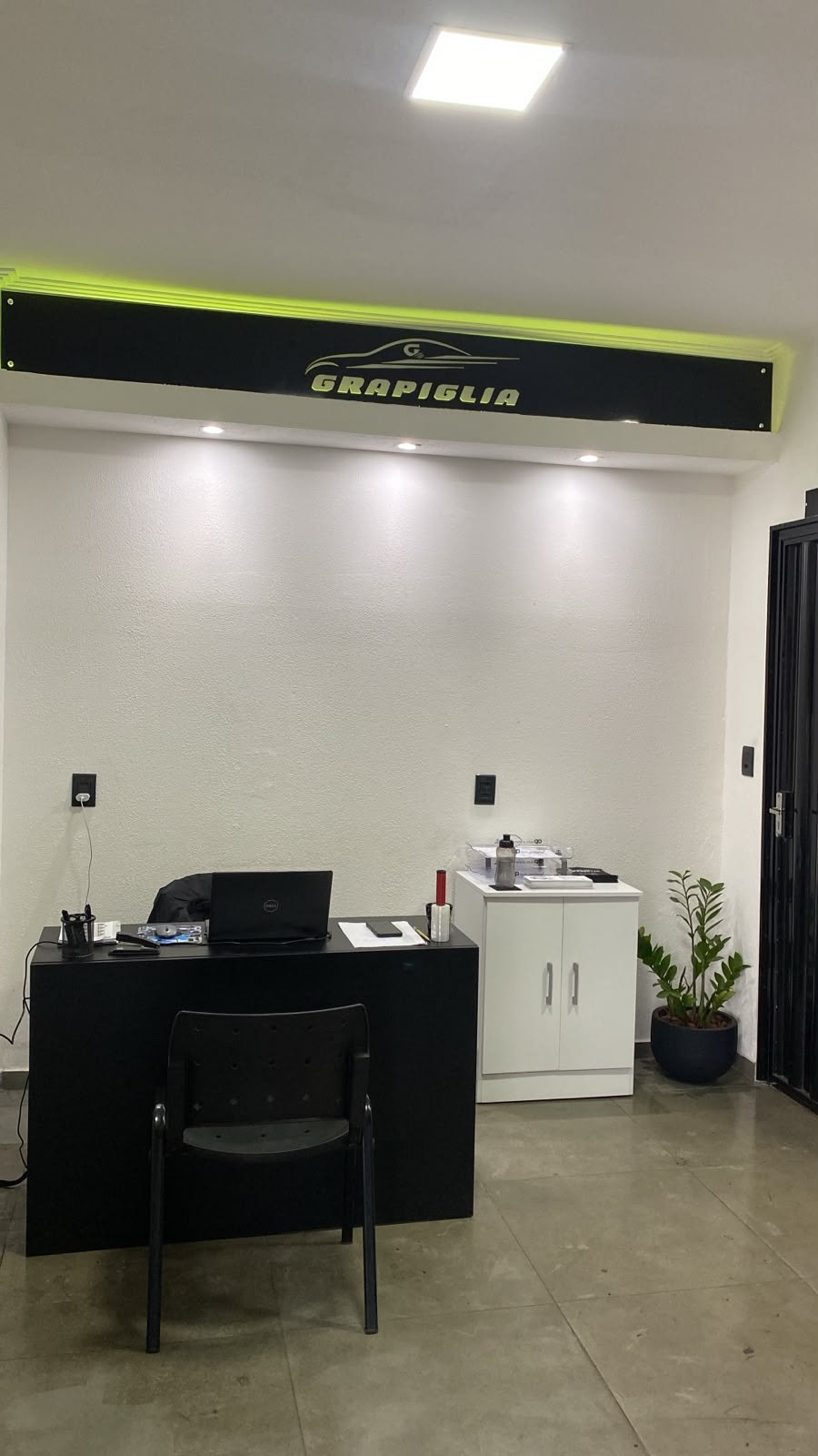 Recepção da Grapiglia com balcão de atendimento e a marca na parede